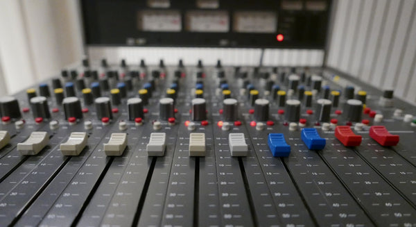 Sound Liaison recording DSD256 iand Analogue mixing. Studer 962. A close-up of a professional audio mixing board with faders, rotary knobs, and colored mute switches in blue, red, yellow, and white.